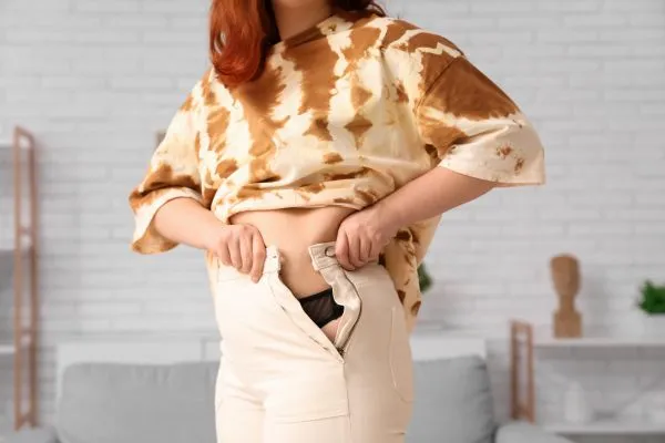 Image of woman trying to do her trousers up after pregnancy weight gain East Retford